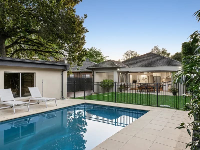 Backyard pool and lawn behind a family home in Glen Iris